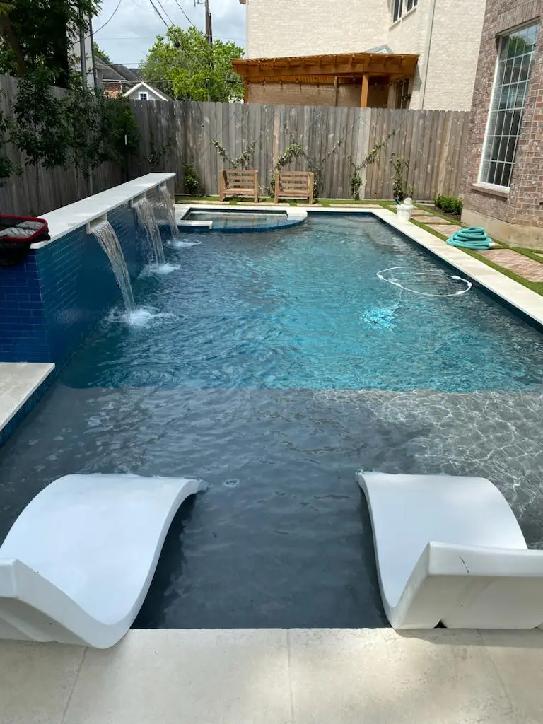 Modern pool with waterfall wall and loungers